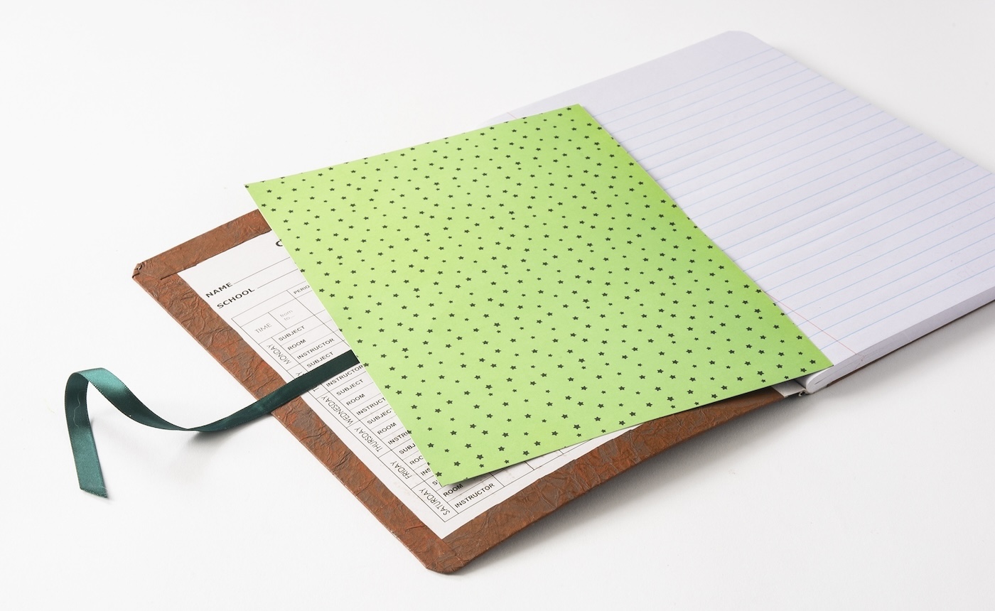 Gluing ribbon and scrapbook paper to the inside cover of the notebook